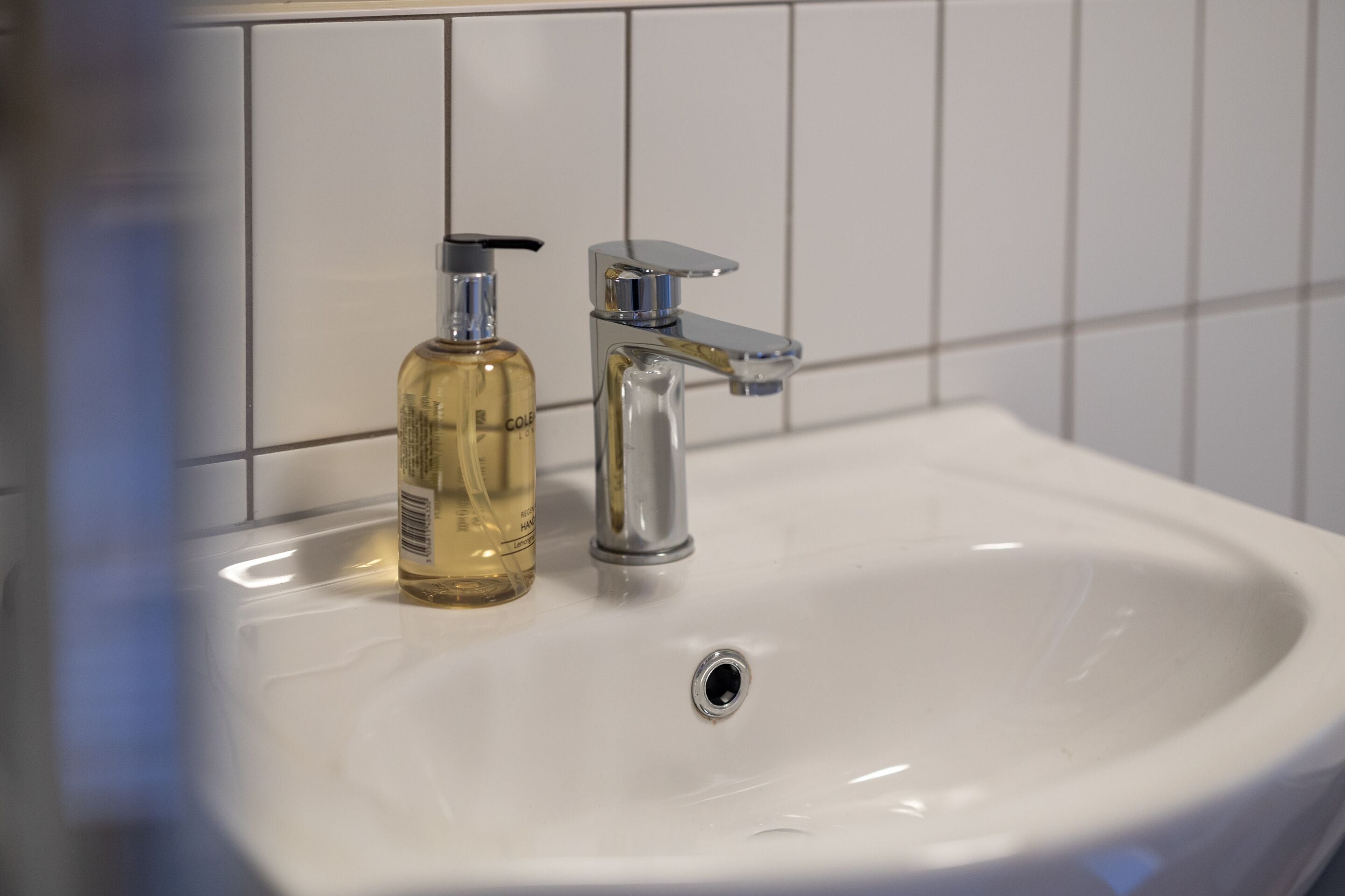 En vask med kromarmatur og en flaske håndsæbe.