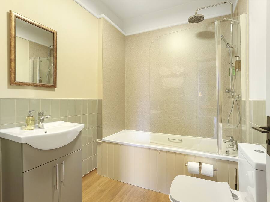Een badkamer met een wastafel, spiegel, douche en toilet.