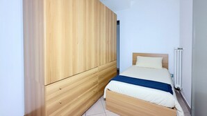 Een slaapkamer met een houten garderobe, een bed met een blauwe deken en een radiator.