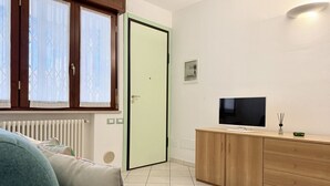 Een moderne woonkamer met een bank, een televisie, een kast en een deur.