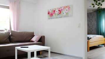 Een moderne woonkamer met een bank, een klein wit tafeltje en een schilderij aan de muur.