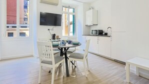 A modern kitchen with white cabinets, a microwave, and a dining area with a table and chairs. - Tuscolana Costantino's Apartment by Rentbeat (Roma)