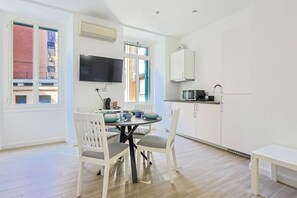 A modern kitchen with white cabinets, a microwave, and a dining area with a table and chairs. - Tuscolana Costantino's Apartment by Rentbeat (Roma)
