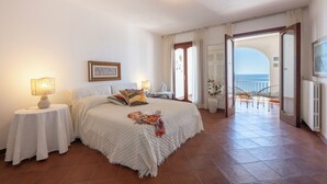 A bedroom with a bed, bedside tables, a nightstand, a window with curtains, and an open door leading to a balcony with a view of the sea. - Villa Les Paons - Downtown Positano - Terrace (Positano)