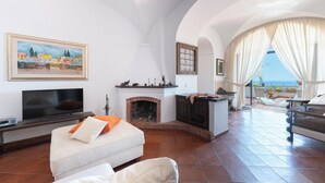 A living room with a fireplace, a television, and a view of the sea. - Villa Les Paons - Downtown Positano - Terrace (Positano)