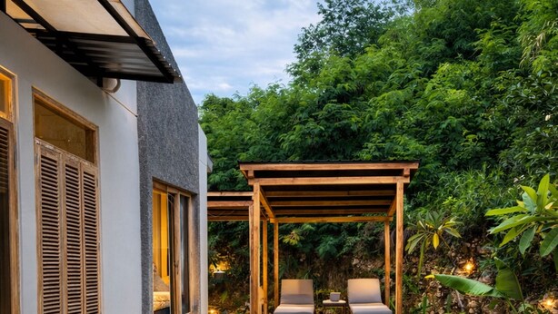 Et moderne poolområde med et pergola, liggestole og en stenhækked sti, der fører hen til poolen.