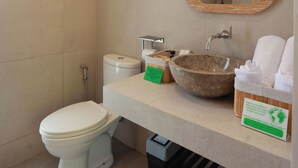Et badeværelse med toilet, håndvask, spejl, håndklædestang og et skilt.