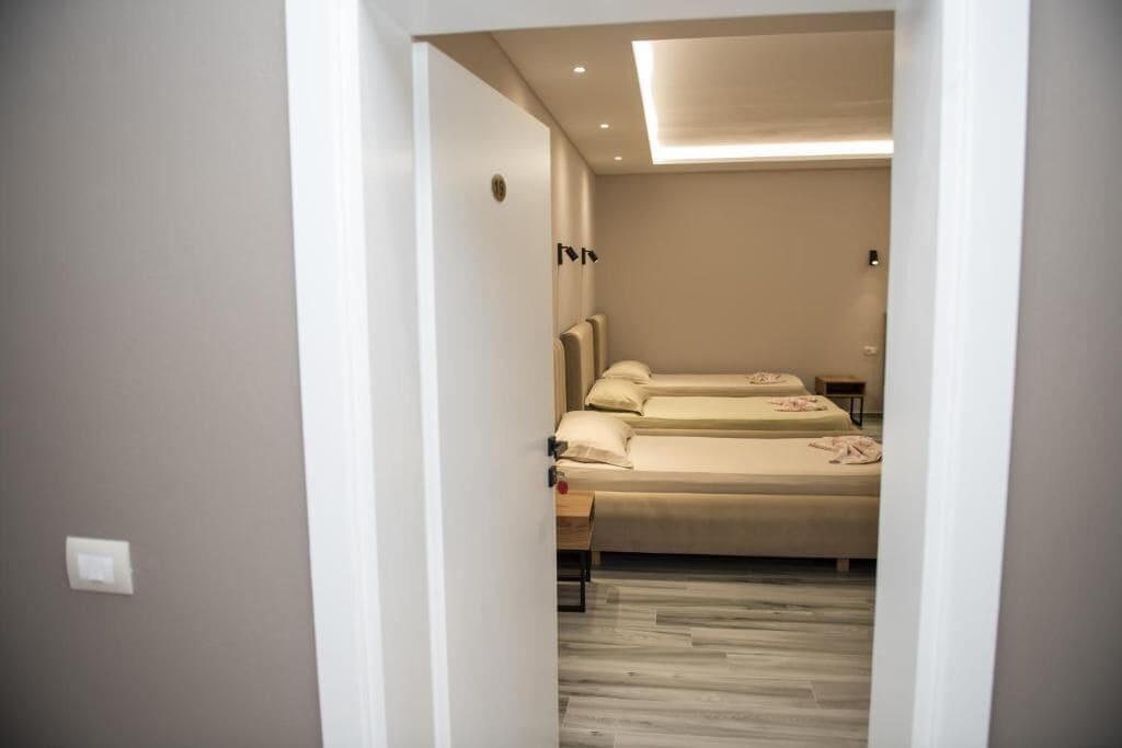 Una habitación de hotel moderna con una cama, mesitas de noche y una lámpara en el techo.