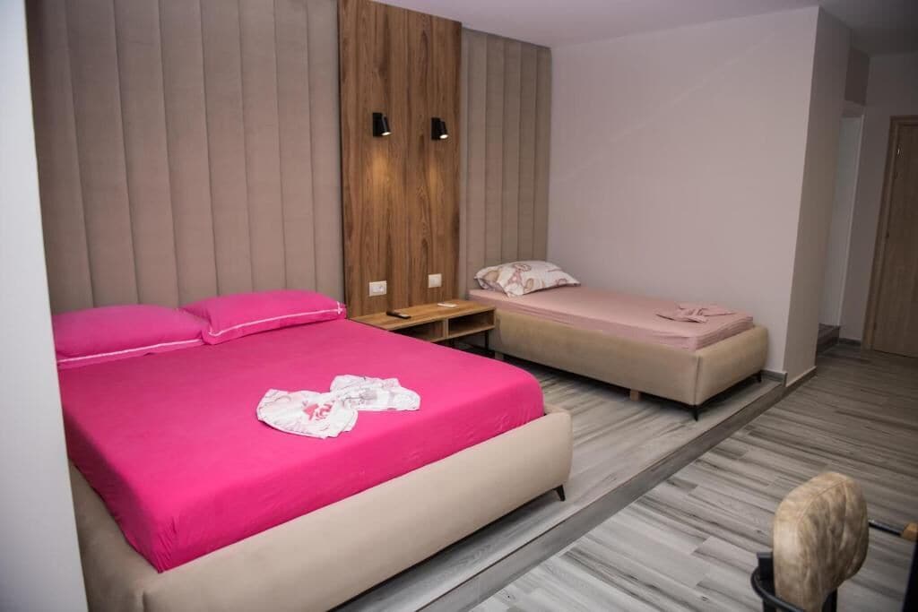 Un dormitorio con una cama grande, una cama más pequeña, un armario y una silla.