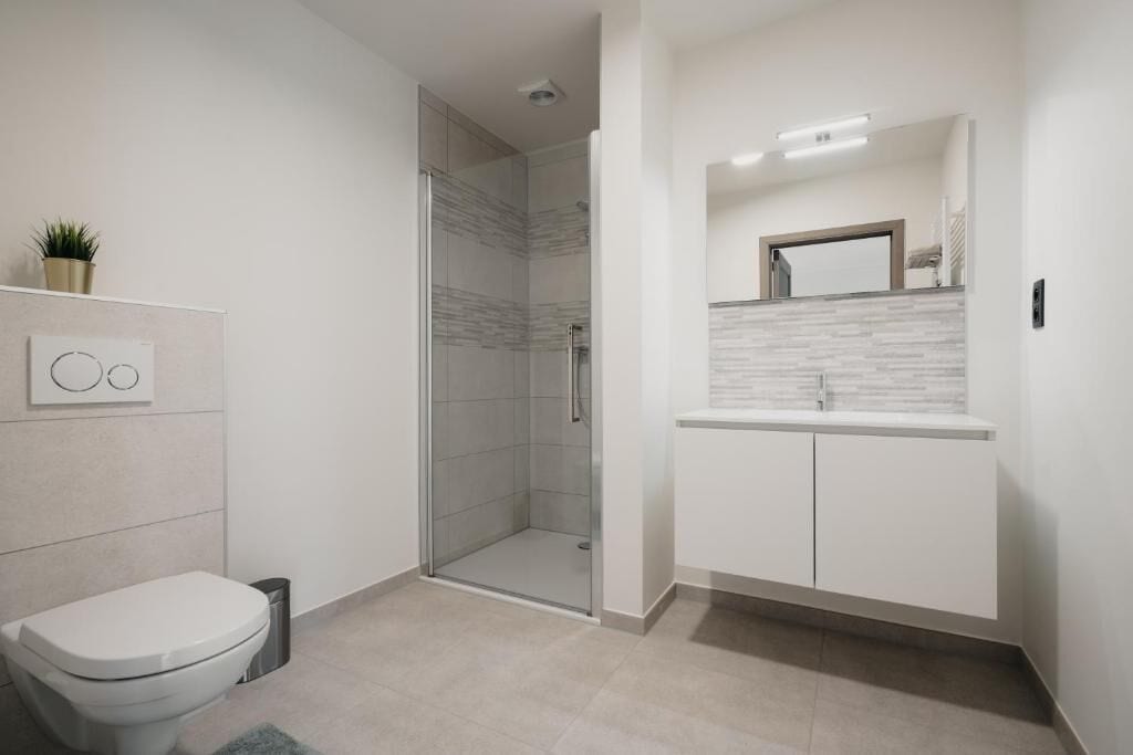 Un baño moderno con inodoro, ducha y tocador.