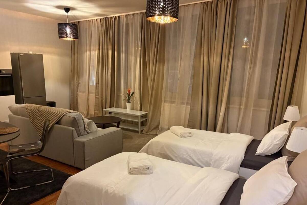 A hotel room with two beds, a sofa, a desk, a TV, and a dining area.