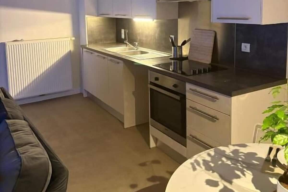 A compact kitchen with white cabinets, a built-in oven, and a sink.