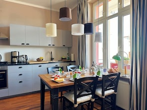 Eine moderne Küche mit weißen Schränken, einem Holzespeisetisch und hängenden Pendelleuchten.