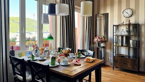 Ruokailutilassa on puinen pöytä, tuoleja sekä erilaisia ruokia ja juomia. Tilassa on myös riippuvalaisimia, seinäkello ja hylly, jossa on koriste-esineitä.