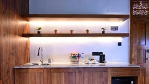 A kitchen with wooden cabinets, a built-in dishwasher, and a countertop with various items. - Meadow Hills Villa by Mahaprana (Sukasada)