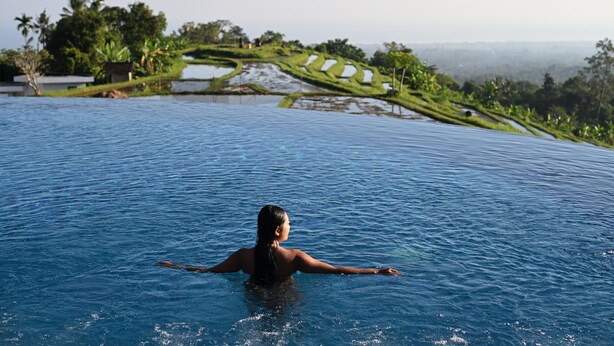 A person in a swimming pool with terraced fields in the background. - Meadow Hills Villa by Mahaprana (Sukasada)