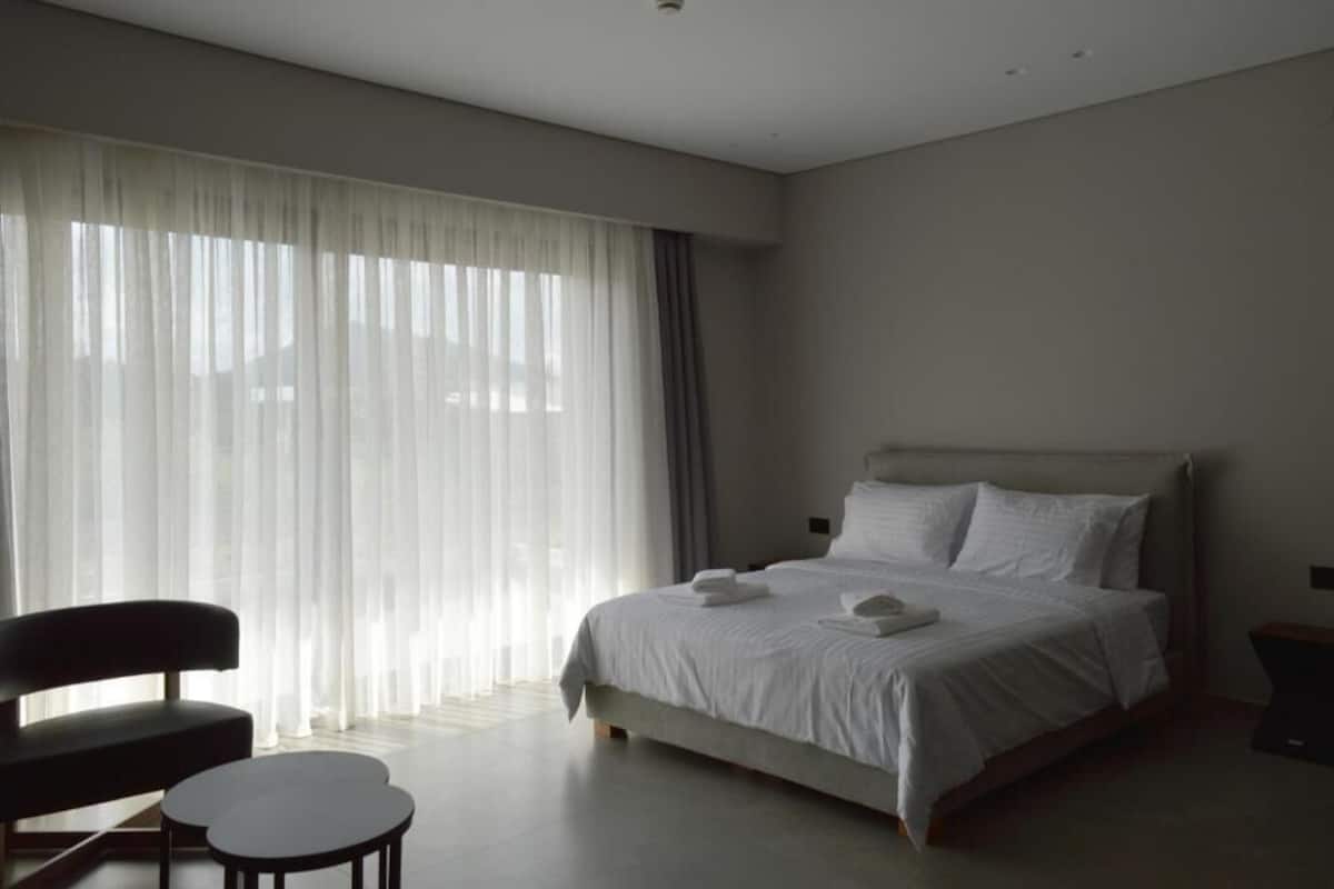 A bedroom with a bed, a chair, and a small table.