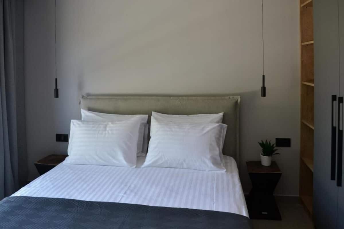 A neatly made bed with white linens, a headboard, and two bedside tables with lamps.