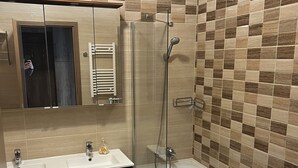 A bathroom with a glass-enclosed shower, a double sink vanity, and a toilet.