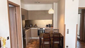 A compact kitchen with a dining area, a coffee machine, and a hanging light fixture.