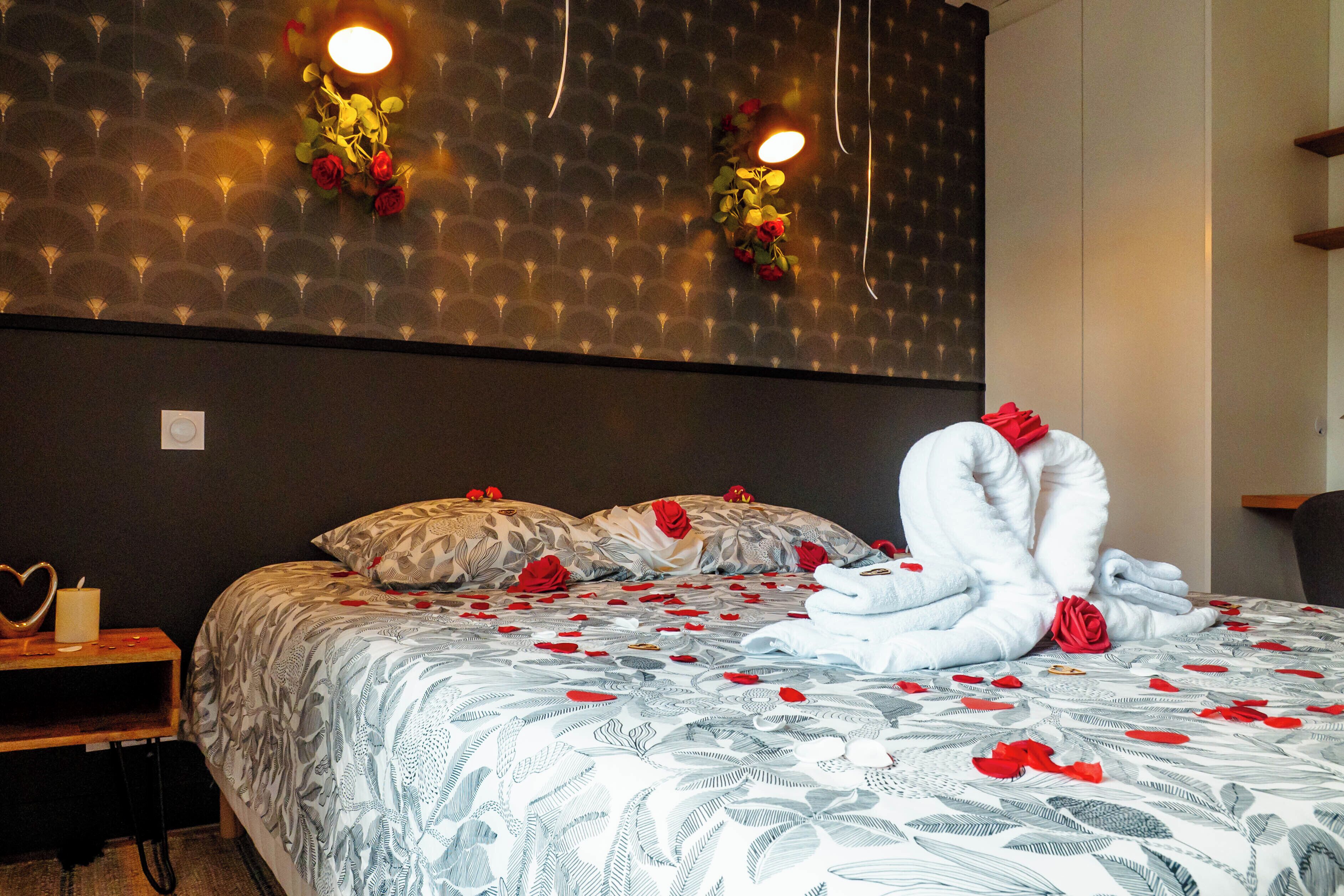 A neatly made bed with a floral bedspread, two pillows, and a bouquet of flowers on the headboard.