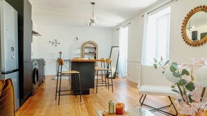 Una cocina moderna con una isla central, taburetes de bar y una zona de comedor con una silla blanca.