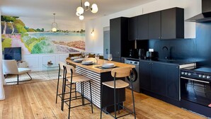 Una cocina moderna con una mesa de comedor de madera, armarios negros y un mural grande con una escena costera.