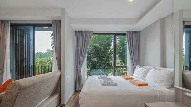 Een hotelkamer met een bed, een slaapbank, een kleine tafel en een groot raam met gordijnen.