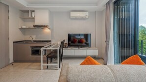 Een moderne keuken met een eetgedeelte, een flatscreen televisie en een groot raam met gordijnen.