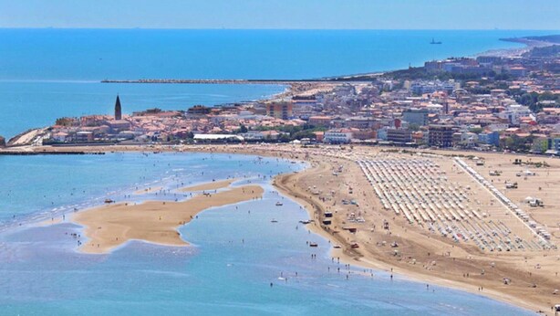 Un paisaje urbano costero con una playa, edificios y una torre destacada.