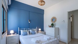 A bedroom with a white bed, two bedside tables with lamps, a dresser, and a mirror on the wall. - Sea Breeze 1-BR Apt & Pool in Pyla (Pyla)