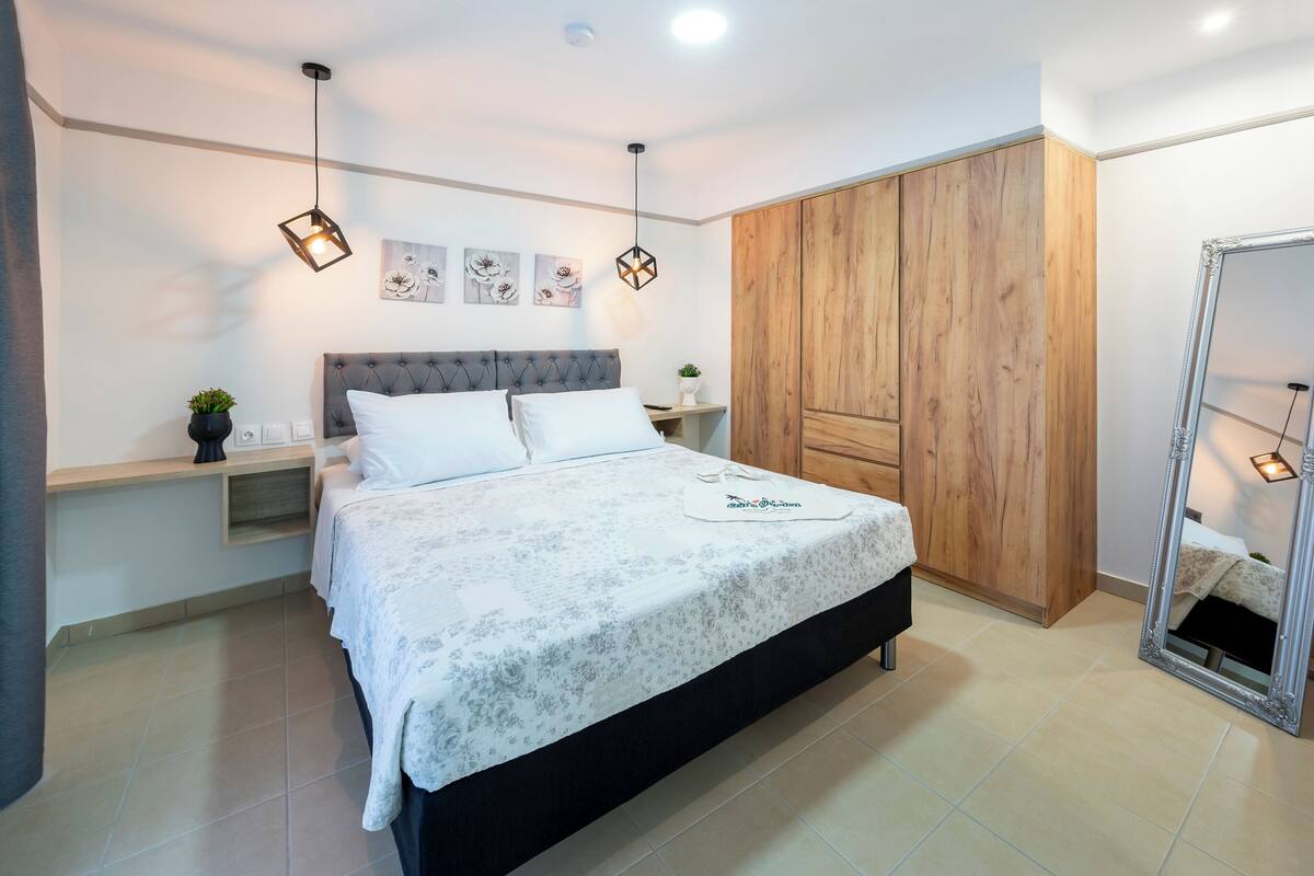 Un dormitorio con cama, mesitas de noche, armario y espejo.