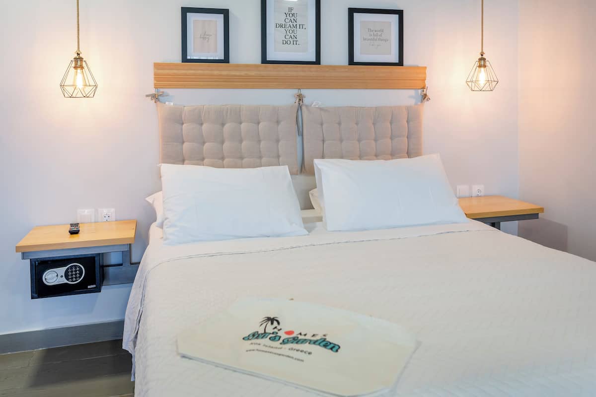 Habitación de hotel con cama, dos mesitas de noche, cabecera de madera y aplique de pared.