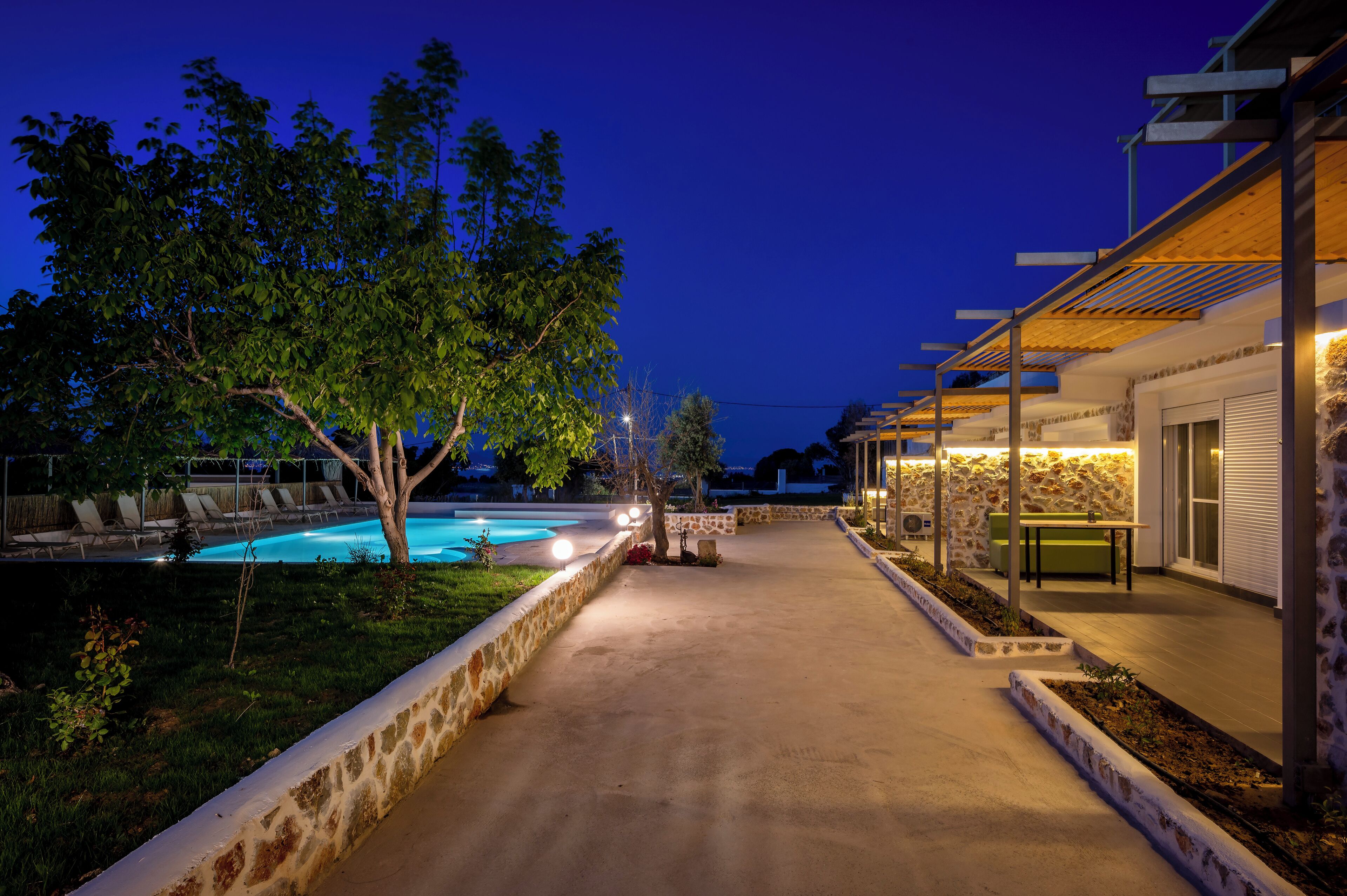 A poolside area with lounge chairs, a stone wall, and a covered seating area.