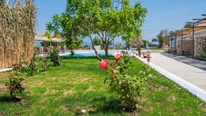 A garden with grass, a tree, and a building with stone walls. - Homes Eva's Garden (Kos)