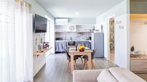 A modern kitchen with a dining area, a flat-screen TV, and a clock on the wall. - Homes Eva's Garden (Kos)