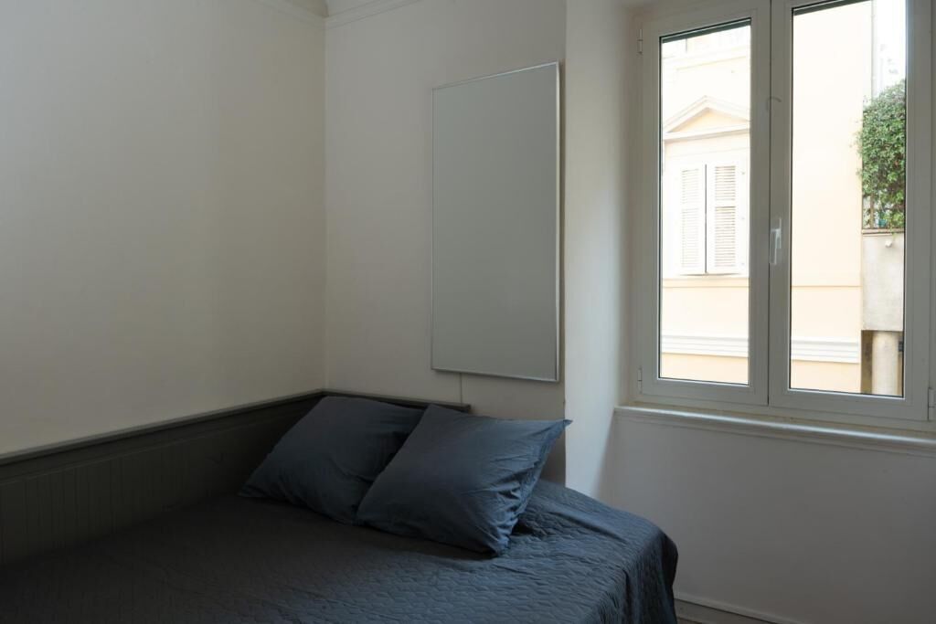 A bedroom with a bed, a window, and a wall-mounted mirror.