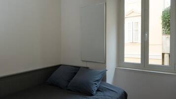 A bedroom with a bed, a window, and a wall-mounted mirror.