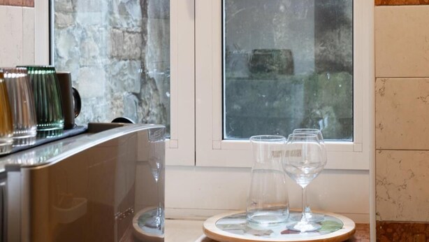 A kitchen area with a countertop, a window with a view, and a set of wine glasses on a coaster. - Casa Castaldi - nel Cuore di Trieste (Trieste)
