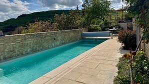 A rectangular swimming pool with a stone wall on one side and a paved deck area. - Villa de luxe La Jonchère, Piscine vue sur les vignes Beaune (Auxey-Duresses)