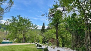 A well-maintained garden with a variety of trees, a lawn, and a gravel pathway. - Villa de luxe La Jonchère, Piscine vue sur les vignes Beaune (Auxey-Duresses)