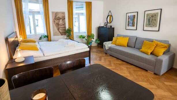 Une chambre d’hôtel moderne, équipée d’un lit, d’un canapé, d’une table à manger et ornée d’œuvres d’art sur les murs.