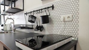 Une cuisine avec un plan de travail noir, un évier blanc et une casserole noire suspendue au mur.
