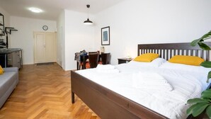Une chambre à coucher avec un lit en bois, un bureau, une chaise, un canapé et une plante.