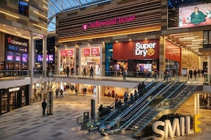 A multi-level shopping mall with stores like Hollywood Bowl, Super Dry, and Uniqlo.