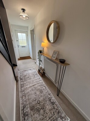 A hallway with a rug, a radiator, a lamp, a mirror, and a door. - Home away from home near NNUH and UEA (Hethersett)
