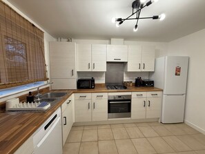 A modern kitchen with white cabinets, a built-in oven, a microwave, a gas stove, and a refrigerator.