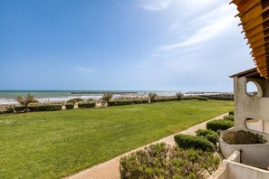 Vista sulla costa con un prato verdeggiante, un vialetto e un edificio dal design architettonico particolare.