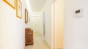 A hallway with white walls, wooden furniture, and a thermostat on the wall. - Casa Maria - vicino a Verona Centro (Verona)