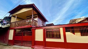 A two-story building with a balcony, a gated entrance, and a satellite dish.